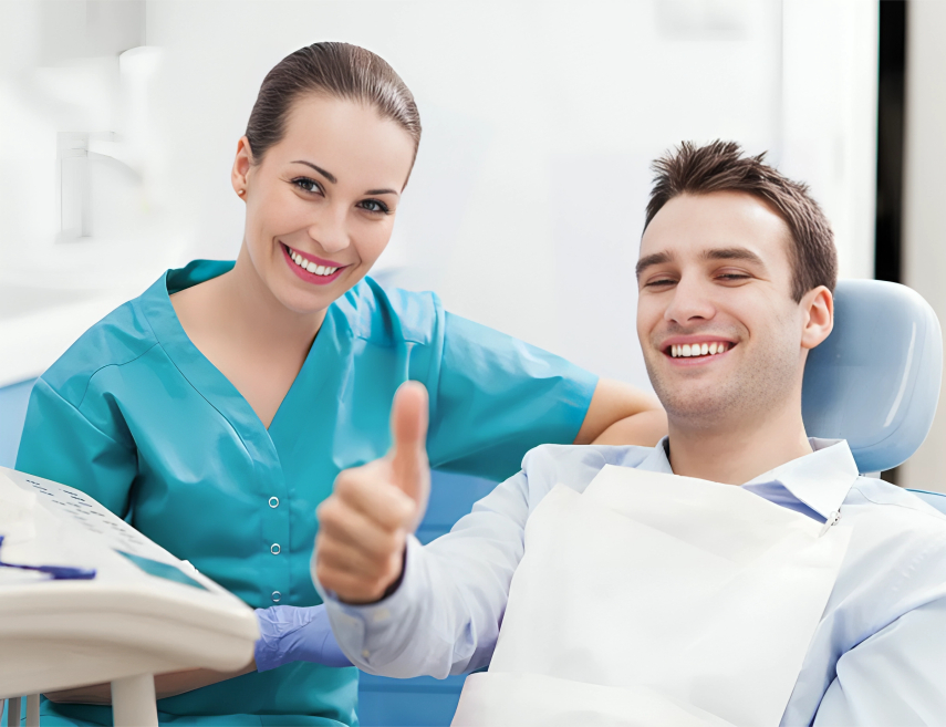 Dental professional in teal scrubs and patient giving thumbs up in modern dental office.